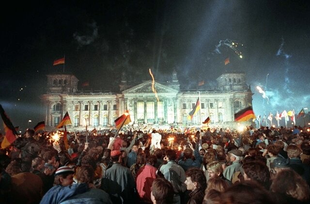 <p>
	<strong>1990:</strong> Einheitsfeiern – Jubelnde Menschenmassen vor dem Berliner Reichstag, die mit Feuerwerk, Deutschlandfahnen und Volksfesttrubel die wiedergewonnene Einheit Deutschlands feiern. Mit dem 3. Oktober sind die Deutschen 45 Jahre nach dem Ende des 2. Weltkrieges wieder vereint.</p>
