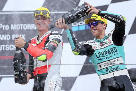 <p>Joan Mir gießt dem spanischen Fahrer Marcos Ramirez nach seinem Sieg in der Moto3 den Champagner in die Kombi.</p>
