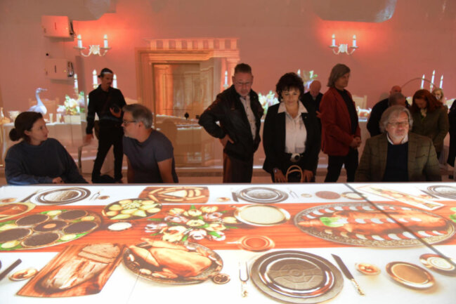 <p>In der Mitte des Kreuzgewölbes, in dem die Projektionsshow gezeigt wird, kann sich der Besucher an einen virtuellen Tisch setzen und Kurfürst Augusts Speisen auf der langen Tafel betrachten.&nbsp;</p>
