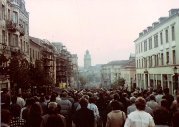 <p>Das Bild entstand während der zweiten Wende-Demo in Plauen am 14. Oktober 1989. Bei der ersten, am 7. Oktober 1989, war verabredet worden, sich eine Woche später wieder zu treffen und friedlich für Reformen in der DDR zu demonstrieren. Transparente sind in der dieser Zeit noch eine absolute Ausnahme.</p>
