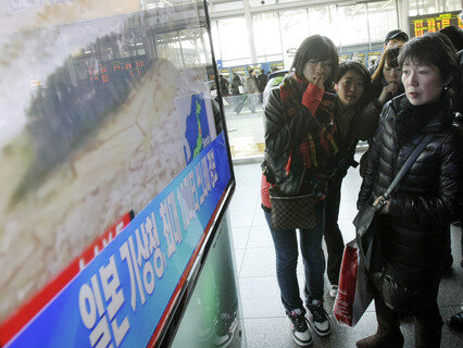 <p>
	Japanische Touristen betrachten die TV-Übertragung der Katastrophenbilder auf einer Eisenbahnstation in Seoul.</p>
