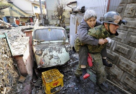 Ein Soldat bringt eine Einwohnerin von Kesennuma in Sicherheit.