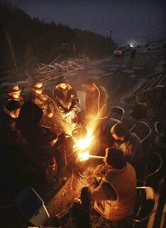 <p>
	Überlebende wärmen sich an einem Feuer in Minamisanriku.</p>
