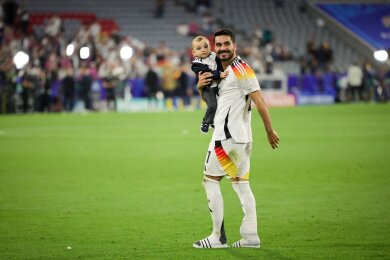 DFB-Kapitän Ilkay Gündogan geht nach dem Spiel gegen Schottland mit seinem Sohn auf dem Arm über den Platz.