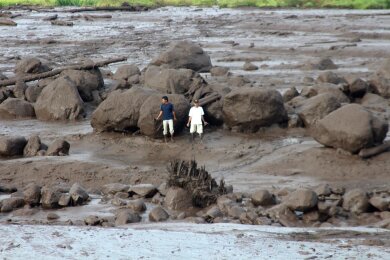 Menschen betrachten ein von einer Sturzflut betroffenes Gebiet in Indonesien. Schwere Regenfälle und Ströme kalter Lava und Schlamm  haben Sturzfluten ausgelöst. Mehr als ein Dutzend Menschen wurden dabei getötet.