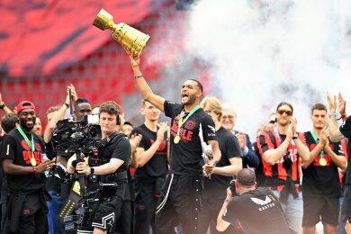 Leverkusens Jonathan Tah (M) präsentiert bei der Meisterfeier in der BayArena die Meisterschale und den Pokal.