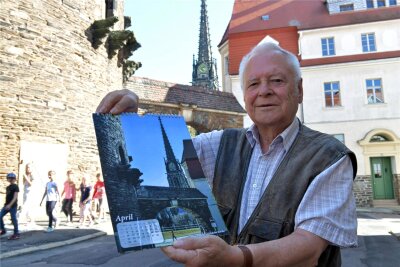 Joachim Link mit seinem Kalender „Freiberger Bilder“ für das Jahr 2024 an der Pfarrgasse in Freiberg.