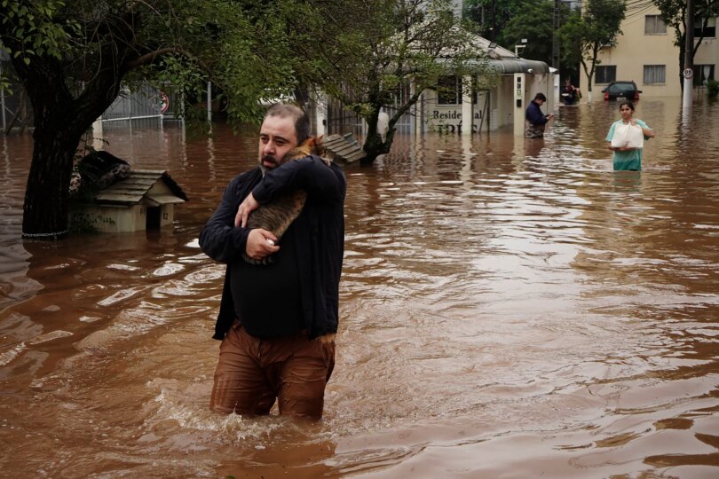 Ein Mann watet durch eine überschwemmte Straße in Brasilien.