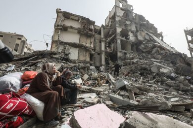 Palästinenserinnen sitzen auf Trümmern im Flüchtlingslager Nuseirat im Gazastreifen nach dem Abzug der israelischen Streitkräfte (IDF).