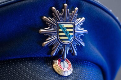 Das Wappen der sächsischen Polizei ist an der Mütze eines Polizisten angebracht.