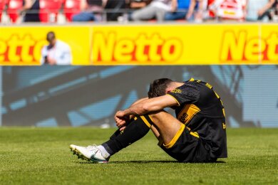 Dynamos Jakob Lewald, der den Elfmeter kurz vor Spielschluss verursachte, sitzt enttäuscht auf dem Rasen.