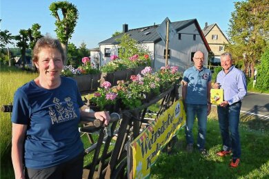 Uta Fischer, Lothar Hähnel und Dirk Spycher (v. l.) am Blumenwagen in Weinsdorf. Alle drei sind Gründungsmitglieder des Heimatvereins, der am Wochenende Jubiläum feiert. 