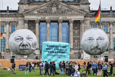 Aktivisten der Entwicklungsorganisation One lassen vor dem Reichstagsgebäude in Berlin zwei Ballons mit den Konterfeis von Kanzler Olaf Scholz (links) und Finanzminister Christian Lindner (rechts) aufsteigen. Mit der Aktion "#LuftNachOben" soll die Bundesregierung an ihre entwicklungspolitischen Versprechen erinnert werden. 