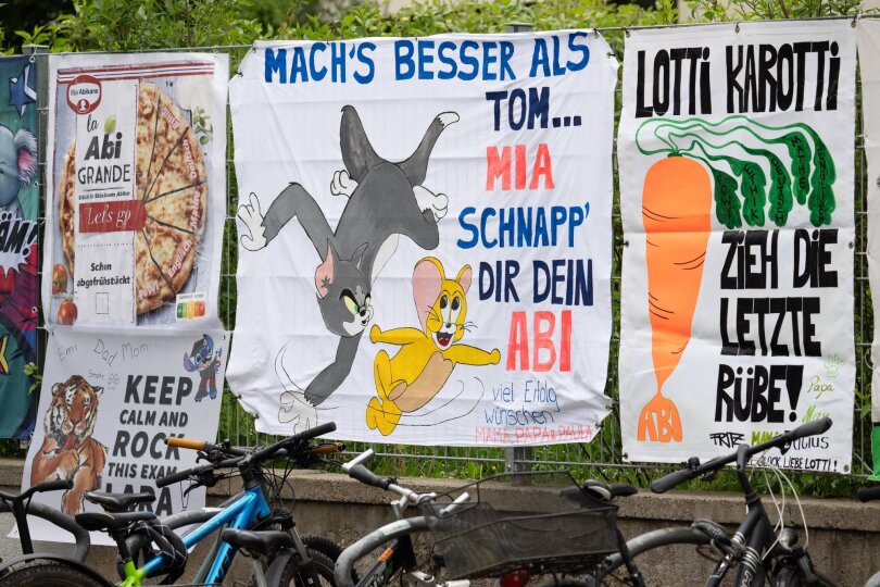 Von Freunden und Eltern gestaltete „Abiplakate“ hängen am Zaun eines Gymnasiums in Frankfurt. In Hessen starten die schriftlichen Abiturprüfungen.