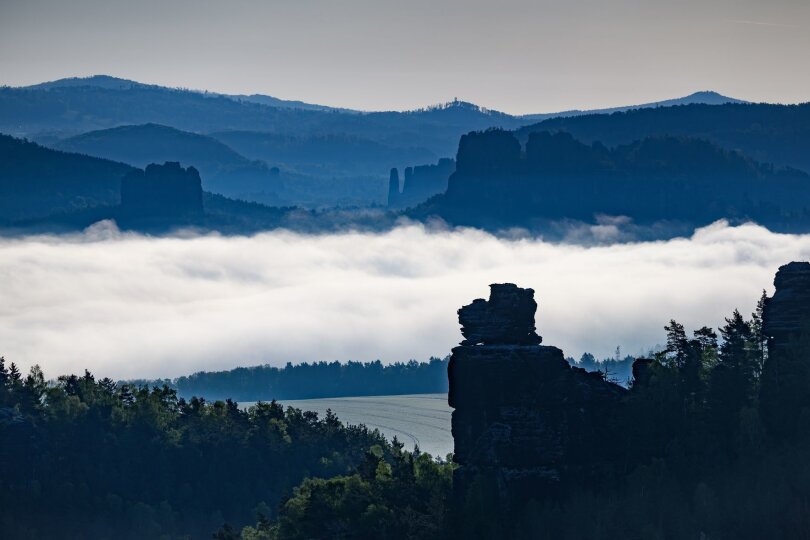 Nebel zieht am Morgen in der Sächsischen Schweiz zwischen Felsen entlang.