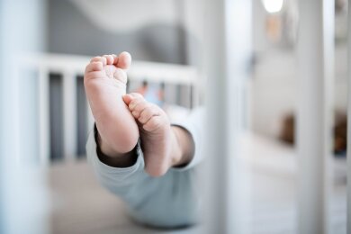 Die Füße eines Babys sind in einem Kinderbett zu sehen.