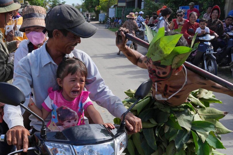 Ein kleines Kind weint, als Reaktion auf einen Mann, dessen Gesicht wie ein Geist bemalt ist. Seine Verkleidung ist Teil einer Schutzgeist-Zeremonie in Phum Boeung, das sogenannte He Neak Ta-Ritual, bei der für Glück, Regen und Wohlstand gebetet wird.