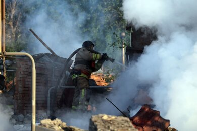 Nach einem russischen Angriff bei Charkiw versuchen ukrainische Rettungskräfte ein Feuer zu löschen.