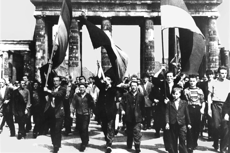 1953: Volksaufstand auch in Sachsen - Ost-Berliner marschieren am 17. Juni 1953 mit wehenden Fahnen vom Ost-Sektor aus durch das Brandenburger Tor. 