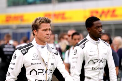 Brad Pitt (l) und Damson Idris gehen bei den Dreharbeiten für einen neuen Formel-1-Film durchs Fahrerlager.