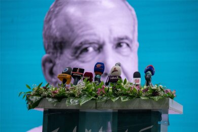 Die Wahlen im Iran könnten spannender werden als gedacht: Ein Bildnis des Präsidentschaftskandidaten Massud Peseschkian ist während einer Wahlkampfveranstaltung hinter einem Rednerpult zu sehen.