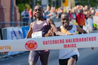 Im letzten Moment gleichauf: Victor Kiptoo (l, Uganda) und Benson Nzioki (Kenia) kommen beim Gutenberg-Halbmarathon in Mainz zur gleichen Zeit ins Ziel und teilen sich nach derzeitigem Stand den ersten Platz.