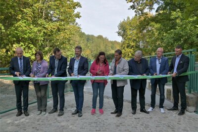 Neun Frauen und Männer haben das Band durchgeschnitten, das extra für die Freigabe der historischen Steinbrücke in Bad Schlema angefertigt wurde.