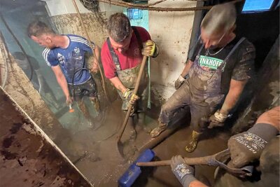 Nach dem Hochwasser räumen Einsatzkräfte Schlamm aus dem Keller eines Einfamilienhauses.