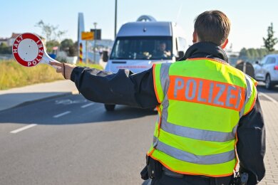 Ein Beamter der Bundespolizei stoppt den Fahrer eines Kleintransporters.