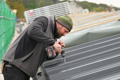 Die Arbeiten auf dem neuen Pultdach gehen voran: Ein Mitarbeiter des Dachdeckermeisters Daniel Hartmann verschraubt ein Trapezblech.