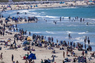 Urlauber und Tagesgäste nutzen das sonnige warme Wetter zu einem Strandbesuch an der Ostseeküste in Warnemünde.