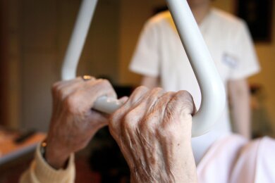 Eine Pflegeheimbewohnerin in einem Seniorenzentrum hält sich in ihrem Bett an einem Haltegriff fest.