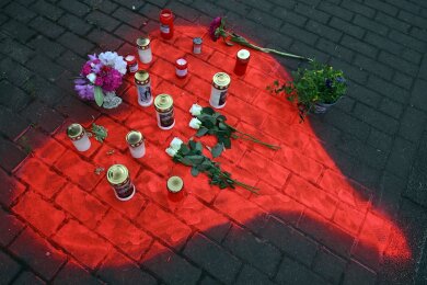 Kerzen und Blumen liegen in einem auf das Pflaster gesprühten roten Herzen in Düsseldorf nach dem mörderischen Brandanschlag.