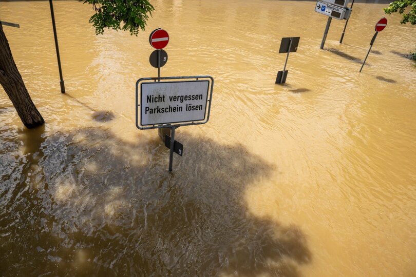 In Bayern herrscht nach heftigen Regenfällen vielerorts weiter Hochwasser. Ein Schild mit der Aufschrift „Nicht vergessen, Parkschein lösen“ in Passau deutet auf einer überfluteten Parkplatz hin.