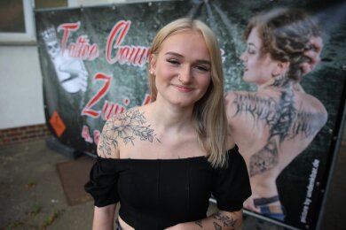 Hübsch anzusehen: Sophie Benti aus Zwickau präsentiert ihre Blumen-Tätowierung auf der rechten Schulter vor dem Plakat der Tattoo Convention Zwickau.