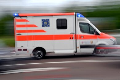 Ein Krankenwagen fährt mit Blaulicht über eine Straße.
