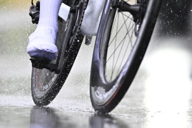 Ein Radfahrer fährt bei Regen über eine Straße.