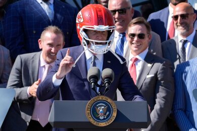 US-Präsident Joe Biden (M) trägt einen Helm von Super-Bowl-Champion Kansas City Chiefs bei einem Besuch im Weißen Haus.