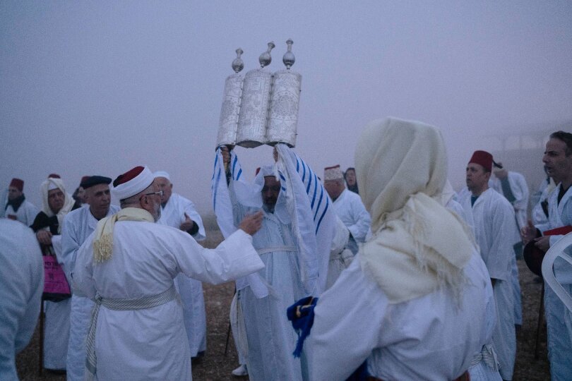 Ein Mitglied der samaritanischen Religionsgemeinschaft hält eine Tora-Schriftrolle hoch. Gäubige beten während der Pessach-Wallfahrt am Berg Garizim in Nablus.