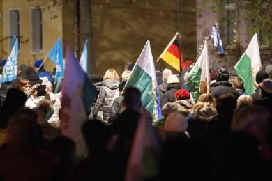 Teilnehmer einer Kundgebung der rechtsextremen Kleinstpartei Freie Sachsen gehen mit verschiedenen Fahnen eine Straße entlang.