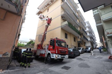 Von einem Hubwagen aus inspiziert ein Feuerwehrmann Schäden an einem Gebäude.