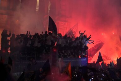 Tausende von Fans jubeln und zünden Feuerwerkskörper, als ein Bus die Spieler von Inter Mailand, die ihren 20. Titel in der italienischen Serie A feiern, vor den Mailander Dom bringt.