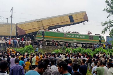 Schaulustige beobachten die Arbeit von Rettungskräften, nachdem ein Güterzug in der Nähe des Bahnhofs von New Jalpaiguri im indischen Bundesstaat Westbengalen einen Personenzug gerammt hat.