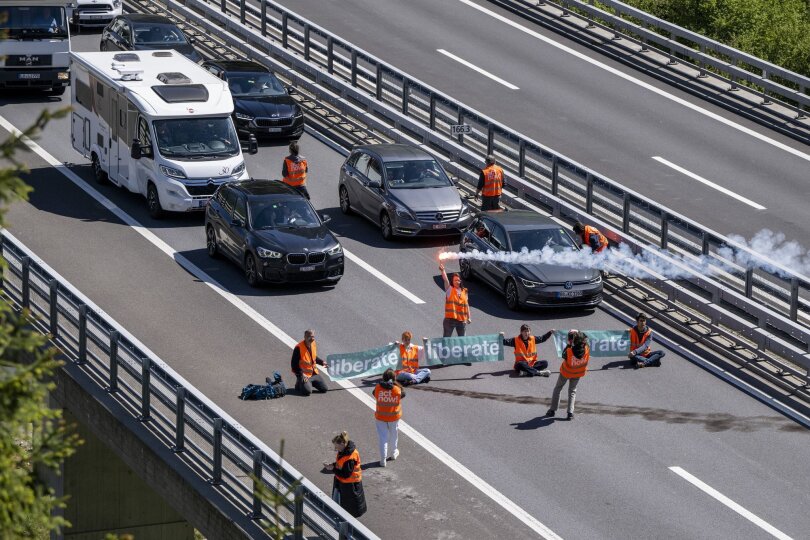 Aktivisten von "Renovate Switzerland" protestieren vor dem Gotthardtunnel im Kanton Uri, während sich der Reiseverkehr auf mehrere Kilometer staut.