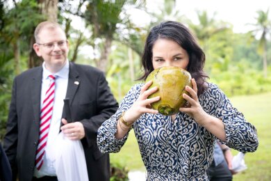 Die deutsche Außenministerin Annalena Baerbock trinkt aus einer Kokosnuss beim Besuch eines Dorfes im Klima-Krisengebiet Fidschi.