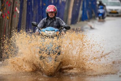Ein Mann bahnt sich in Guwahati, Indien, den Weg durch die Überflutungen nach schweren Monsunregenfällen.