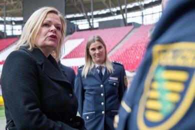 Nancy Faeser (SPD, l), Bundesinnenministerin, unterhält sich in der Leipziger Arena mit Vertretern der Polizei.
