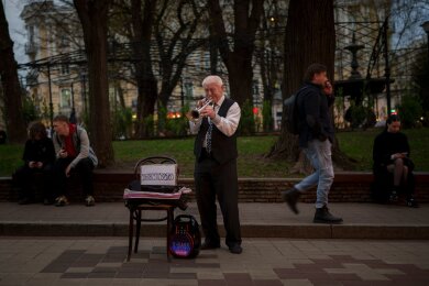 Ein Mann spielt Trompete in einem Park in Kiew, Ukraine.