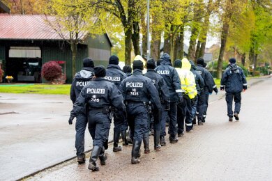 Polizisten gehen auf der Suche nach einem vermissten Jungen durch eine Ortschaft in Niedersachsen.
