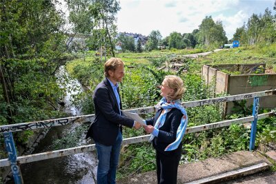 Michael Stötzer empfängt von Regina Kraushaar, Präsidentin der Landesdirektion Sachsen, am 30. August den Fördermittelbescheid auf der Brücke, die nun gesperrt ist.